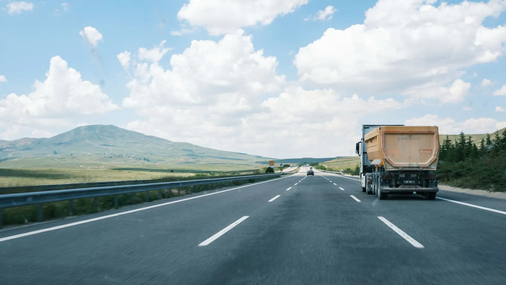 Truck traveling an open highway under a bright blue sky