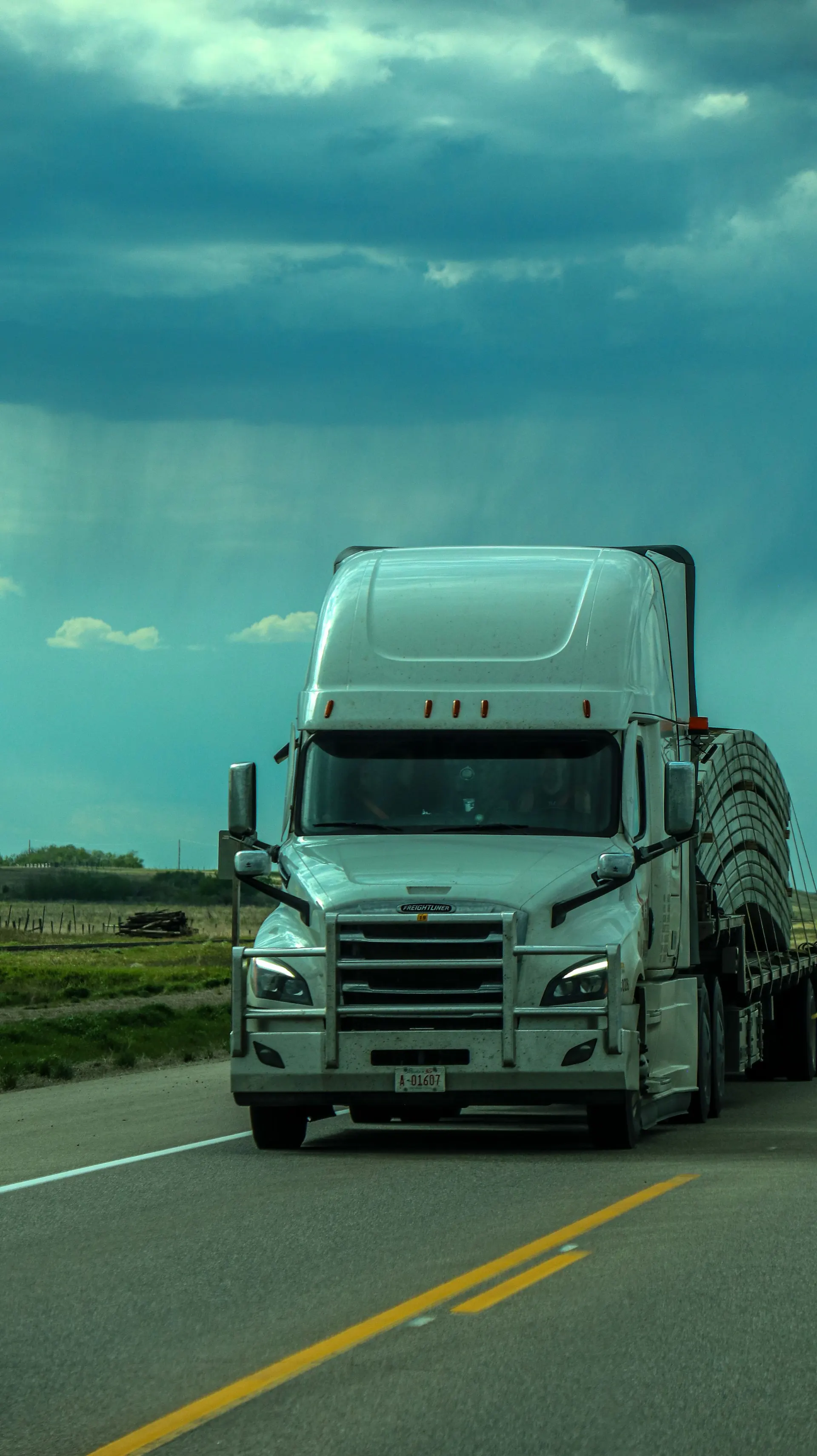 Modern semi-truck traveling a highway under a dramatic cloudy sky